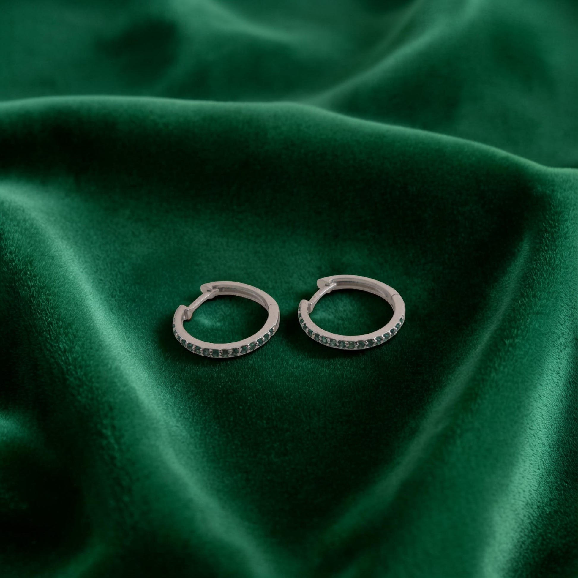 Orecchini in oro bianco 18kt di Meteore Gioielli a forma di cerchio diametro 16mm con una fila di smeraldi naturali taglio brillante incassati a griffes di 0.21ct