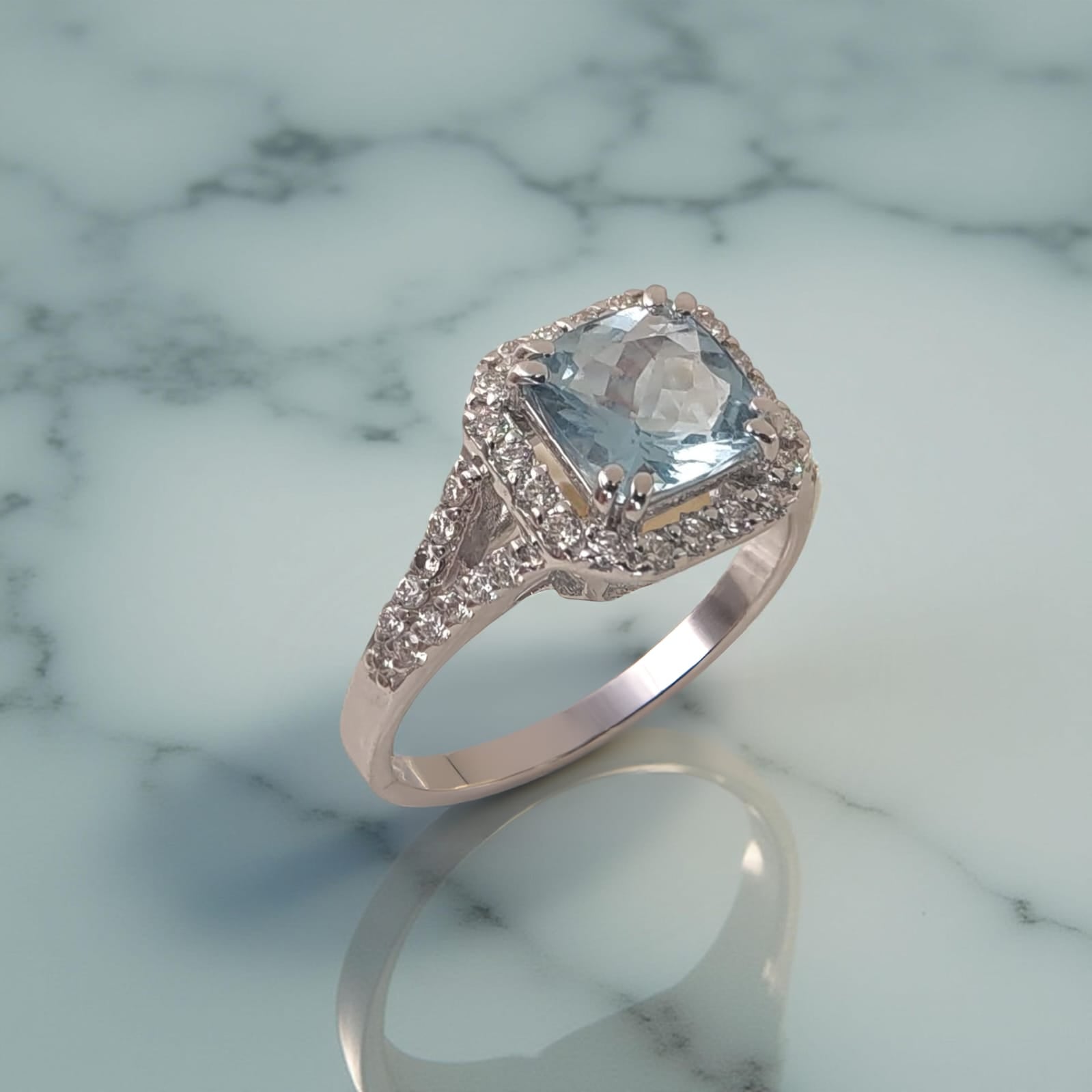 Anello in oro bianco 18kt di Meteore Gioielli presenta al centro una Acquamarina naturale dal taglio cuscino di ct 1.29 e un giro di diamanti naturali 0.50 ct 