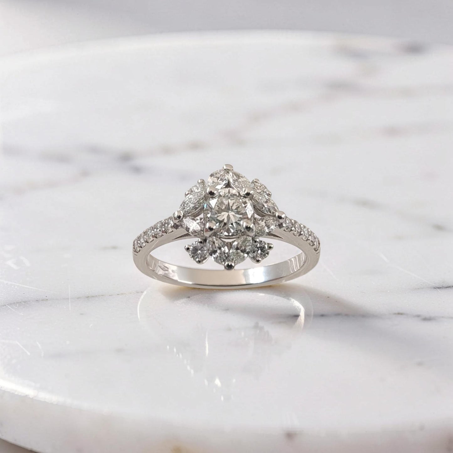 anello in oro bianco 18kt con diamante centrale taglio brillante da 0,51 ct, contornato da diamanti taglio brillante e marquise a forma floreale, firmato meteore gioielli.