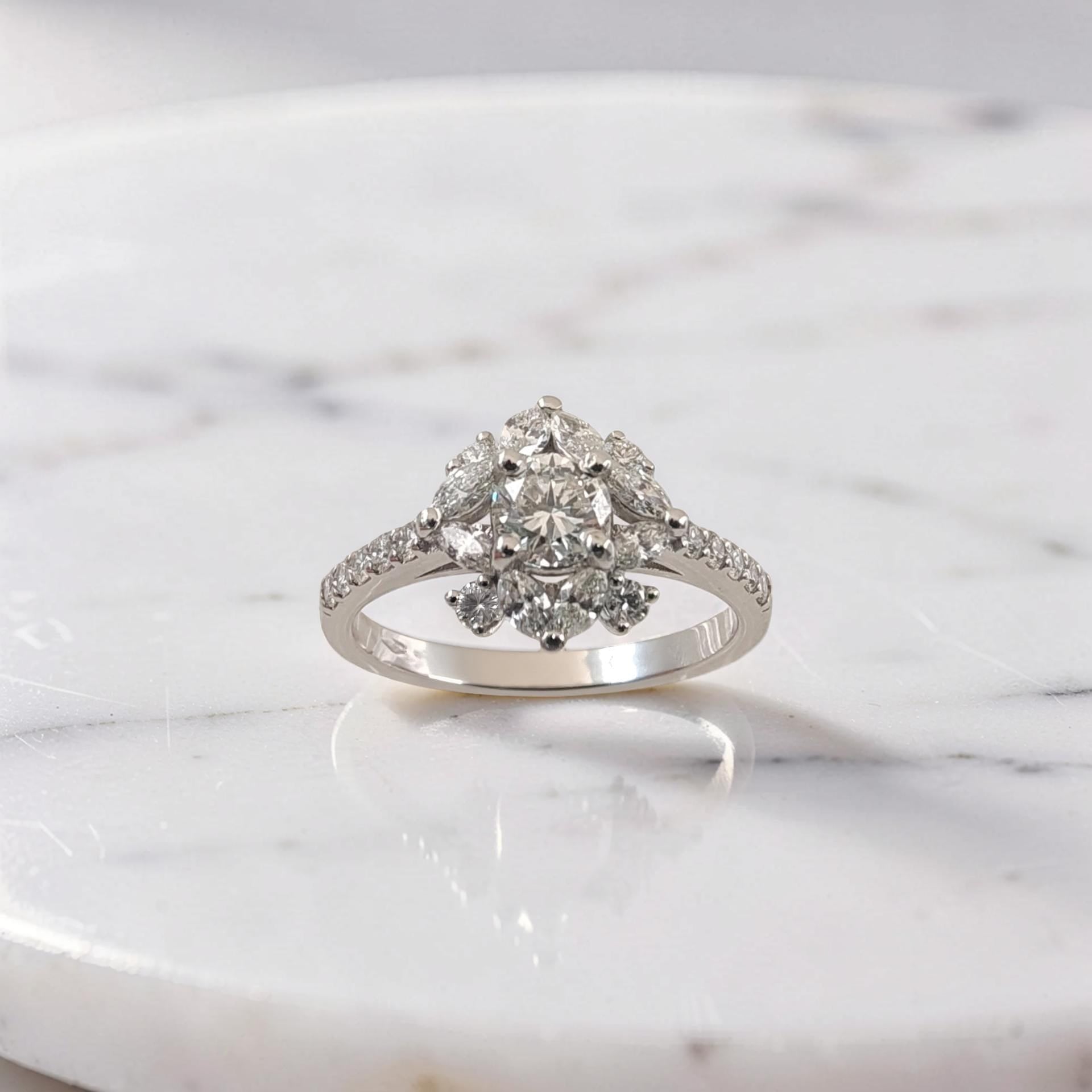 Anello in oro bianco 18Kt con diamante centrale taglio brillante da 0,51 ct, contornato da diamanti taglio brillante e marquise a forma floreale, firmato Meteore Gioielli.