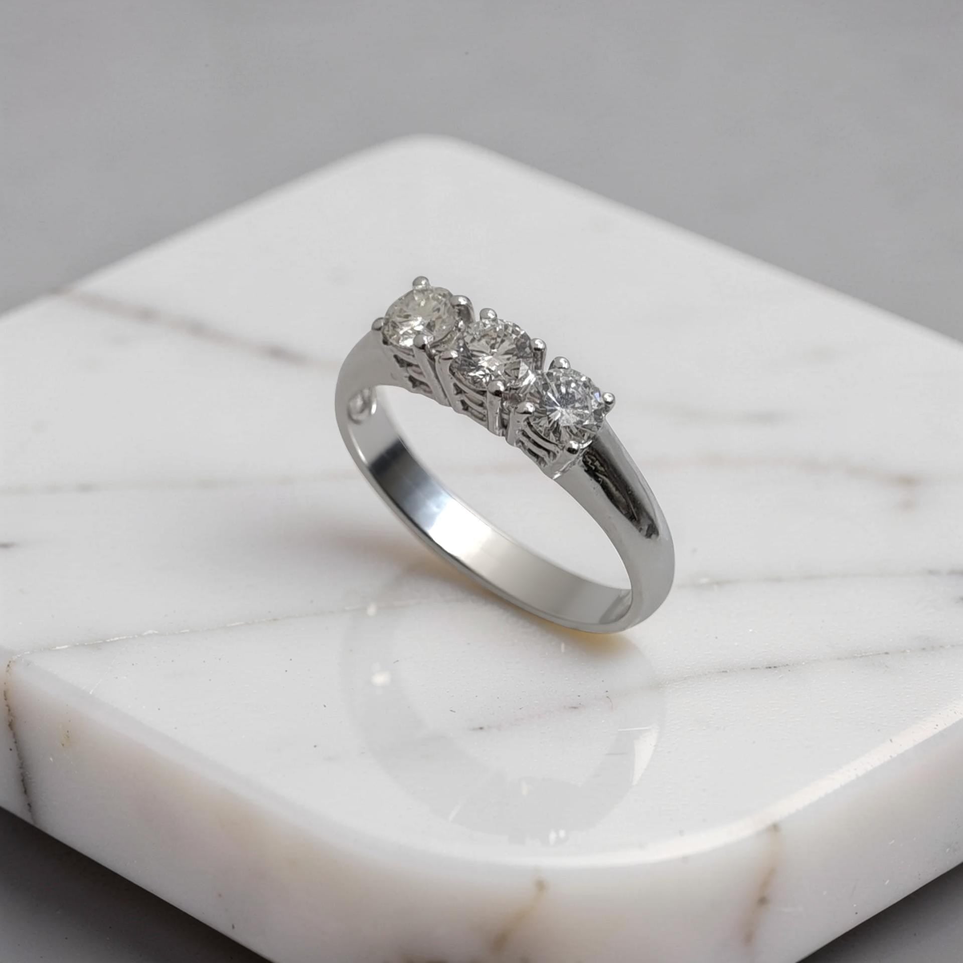 Anello trilogy in oro bianco 18 carati con diamanti naturali taglio brillante su sfondo bianco visto di lato