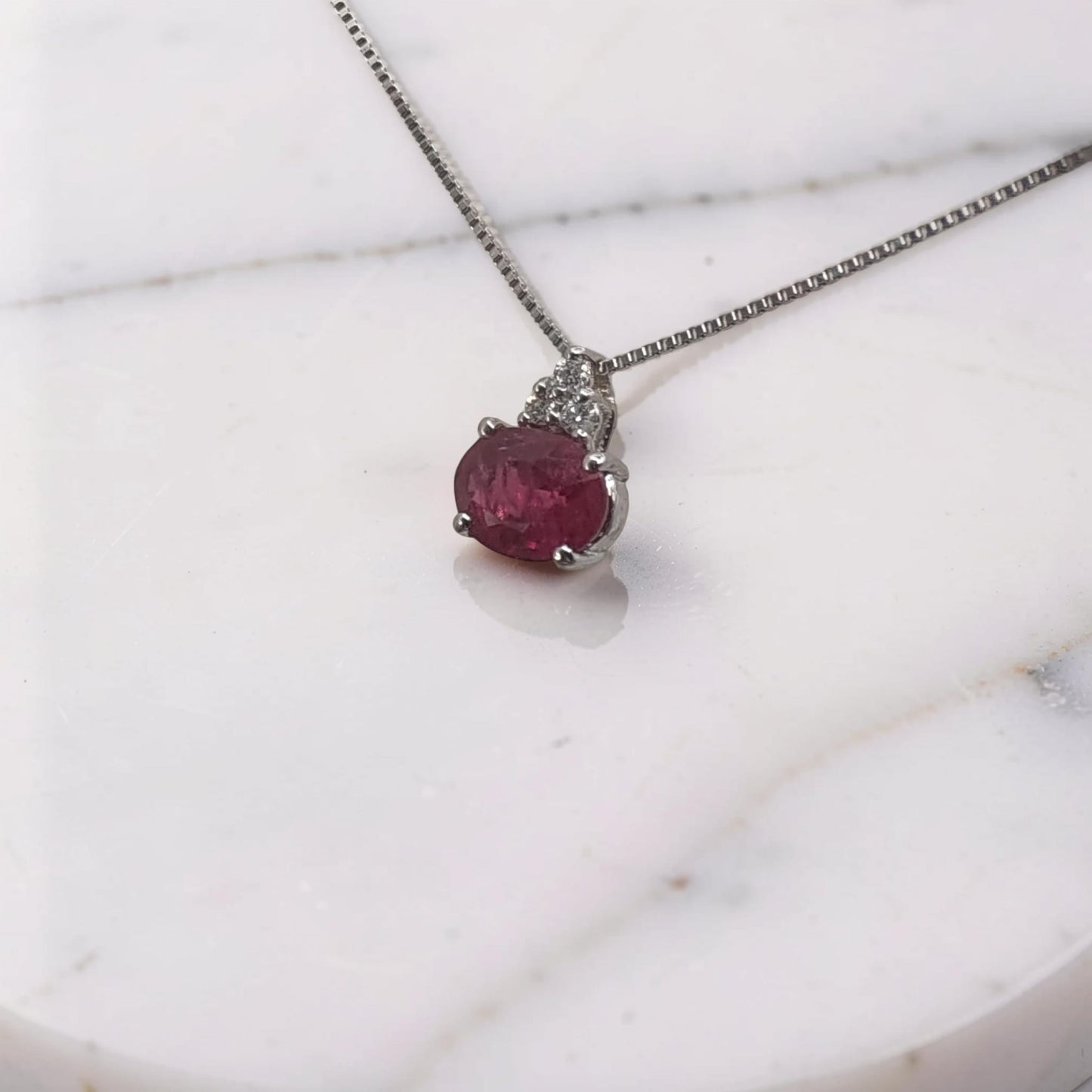 vista laterale collana in oro bianco 18 kt con pendente rubino ovale montato orizzontale da 0,38 ct e tre diamanti a triangolo meteore gioielli