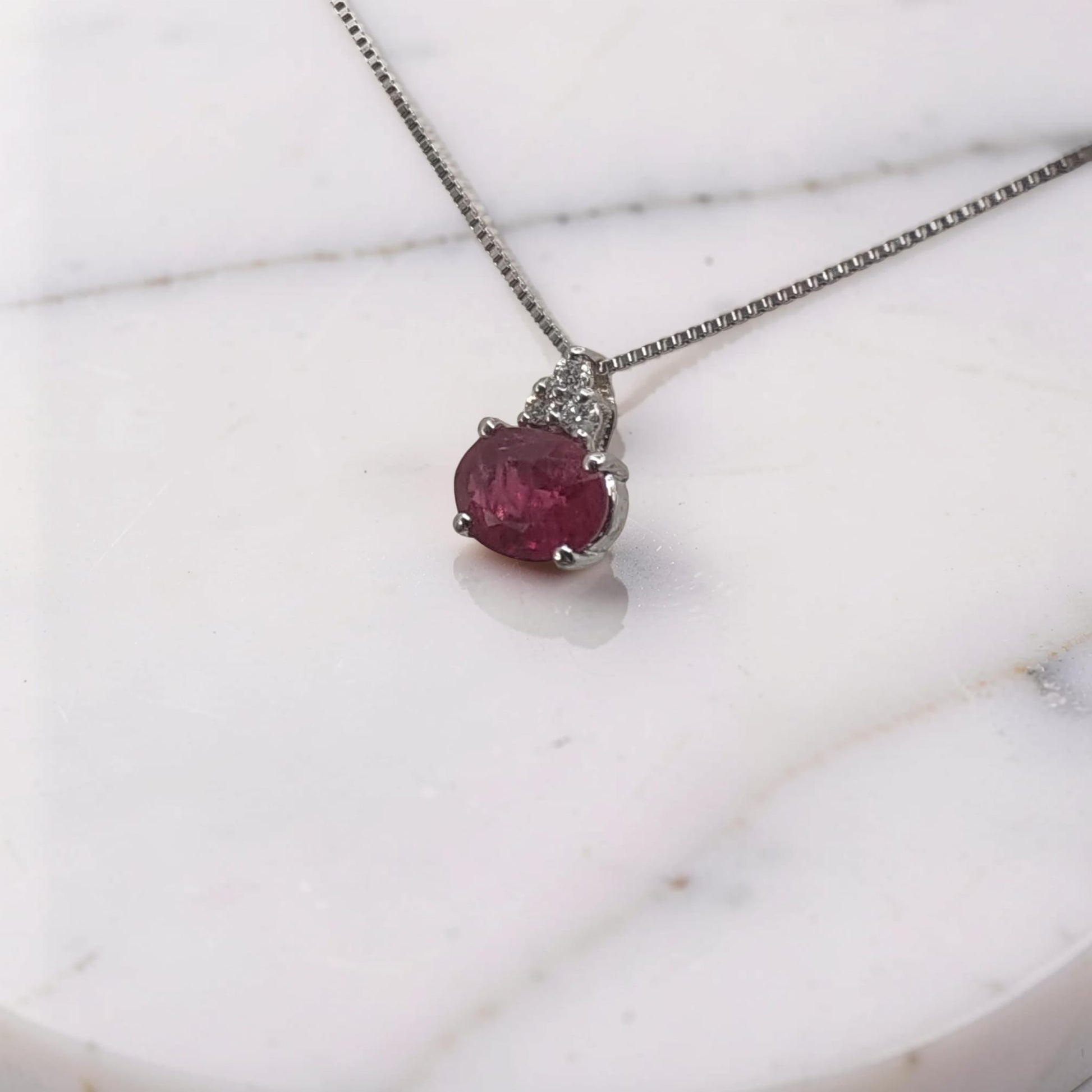 vista laterale Collana in oro bianco 18 KT con pendente rubino ovale montato orizzontale da 0,38 ct e tre diamanti a triangolo Meteore Gioielli