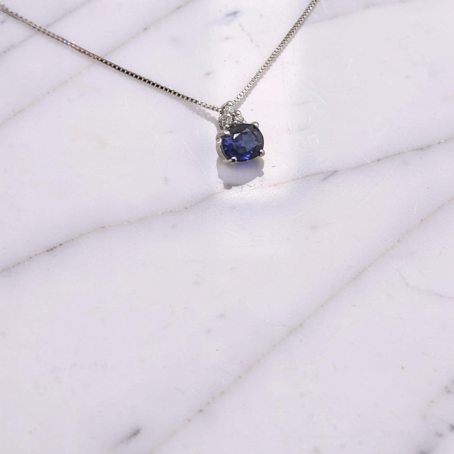 collana in oro bianco 18 kt con zaffiro naturale ovale orizzontale da 0,36 ct e tre diamanti incastonati a triangolo  visto in prospettiva laterale firmata meteore gioielli