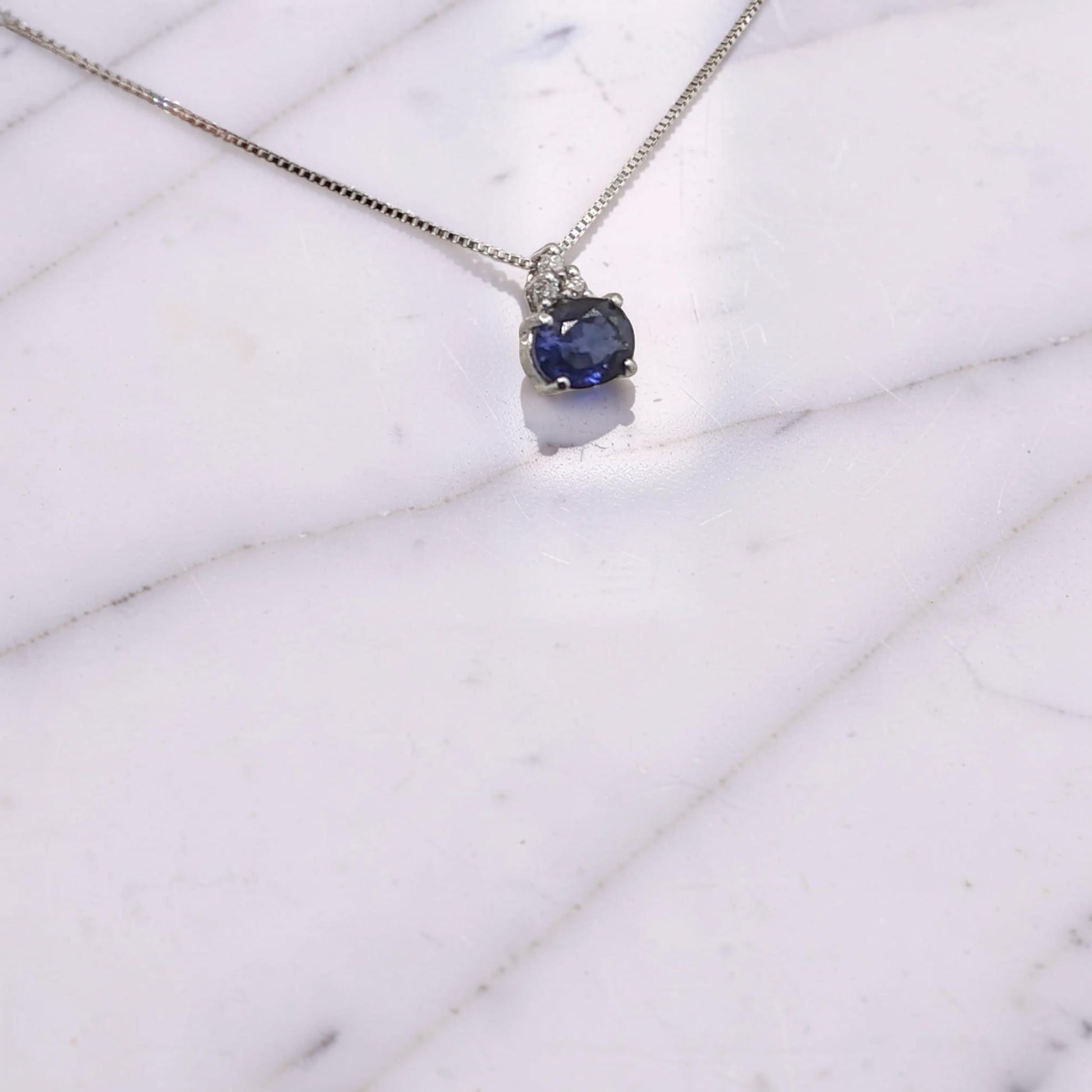 Collana in oro bianco 18 KT con zaffiro naturale ovale orizzontale da 0,36 ct e tre diamanti incastonati a triangolo  visto in prospettiva laterale firmata Meteore Gioielli