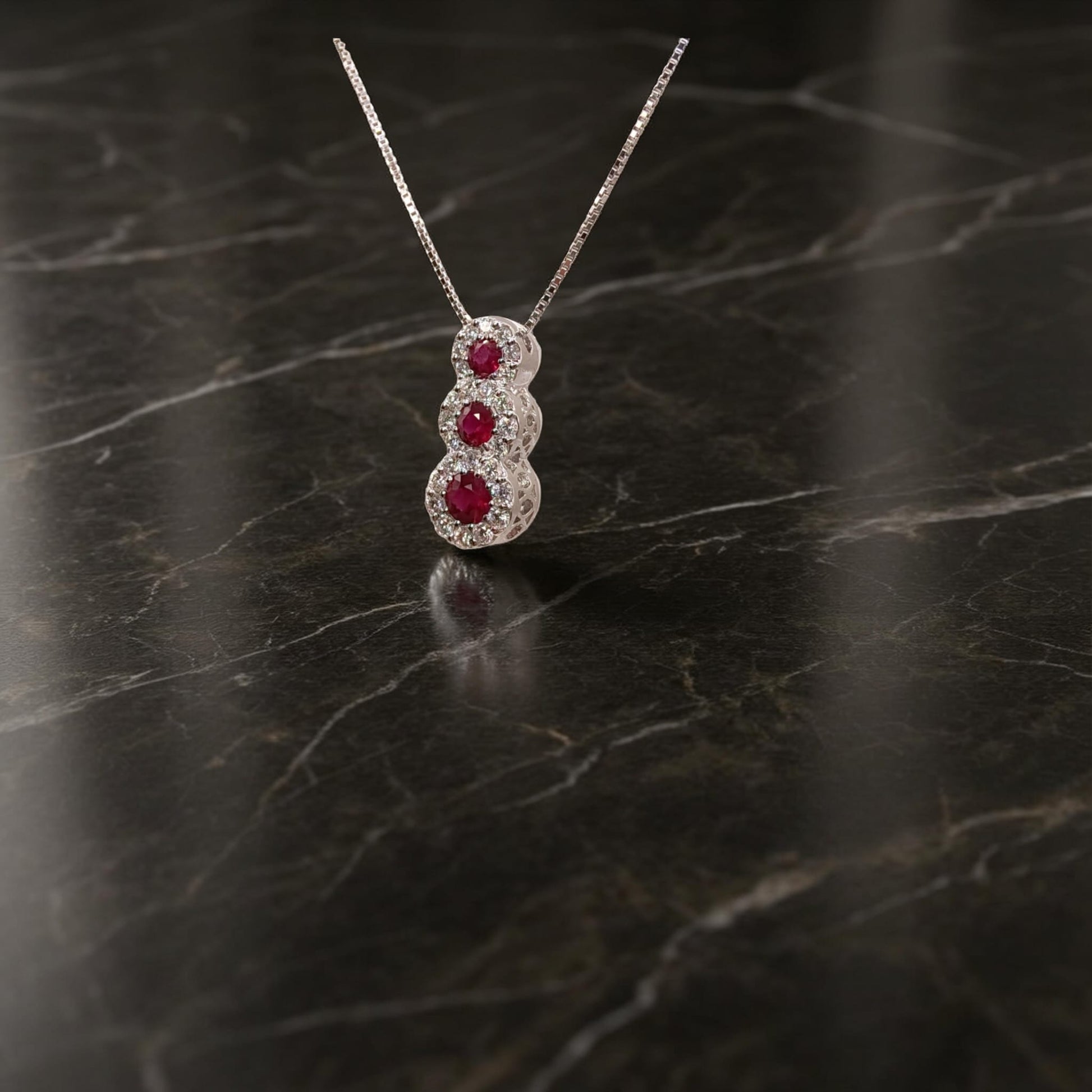 Collana trilogy in oro bianco 18kt di Meteore Gioielli con tre rubini tondi naturali ct0.34 montati a scalare circondati da diamanti naturali  0.22ct .