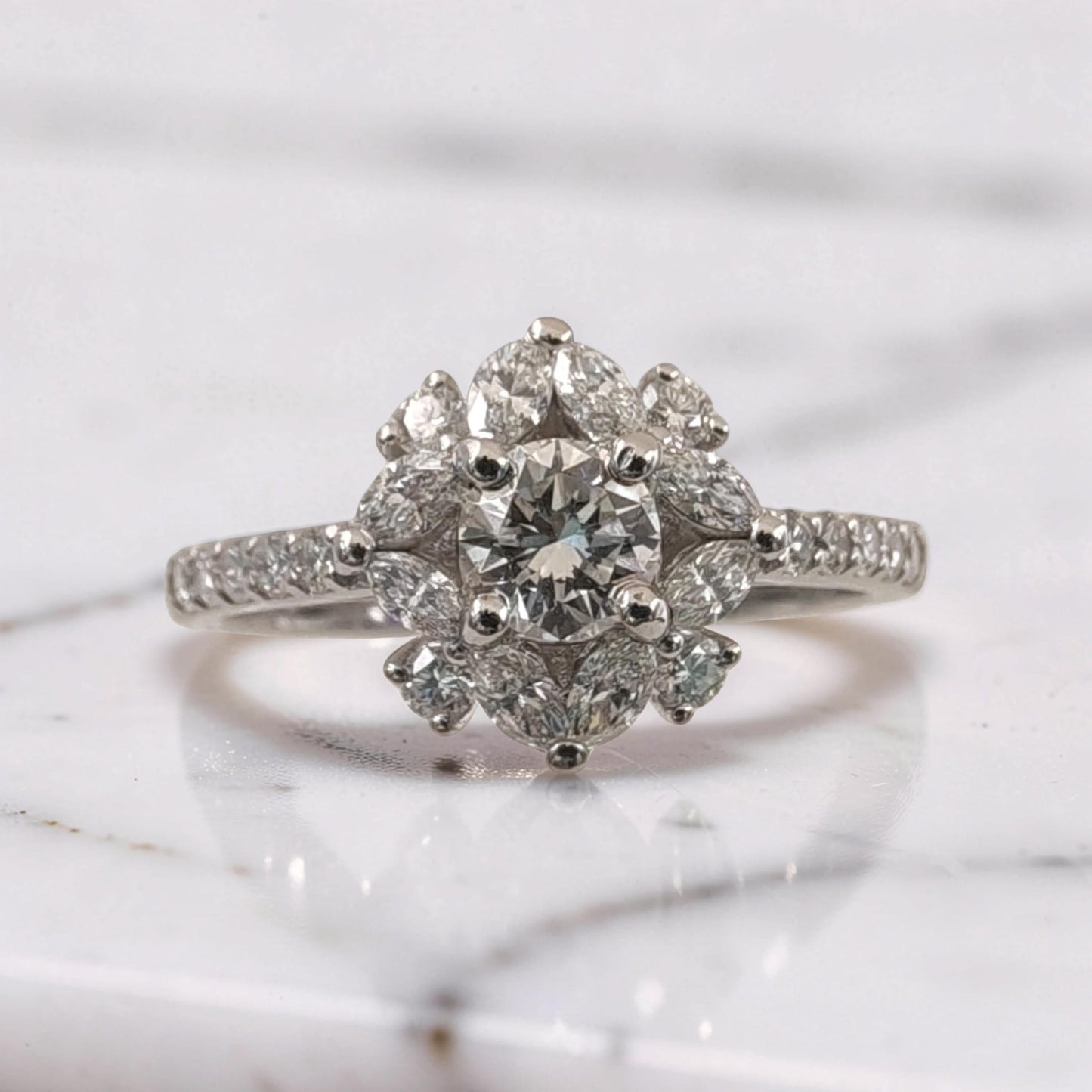 primo piano di anello in oro bianco 18kt con diamante centrale taglio brillante da 0,51 ct, circondato da diamanti taglio brillante e marquise disposti a fiore, dettaglio alta gioielleria meteore gioielli.