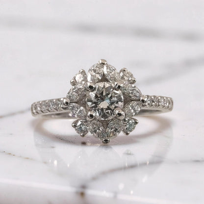Primo piano di anello in oro bianco 18Kt con diamante centrale taglio brillante da 0,51 ct, circondato da diamanti taglio brillante e marquise disposti a fiore, dettaglio alta gioielleria Meteore Gioielli.