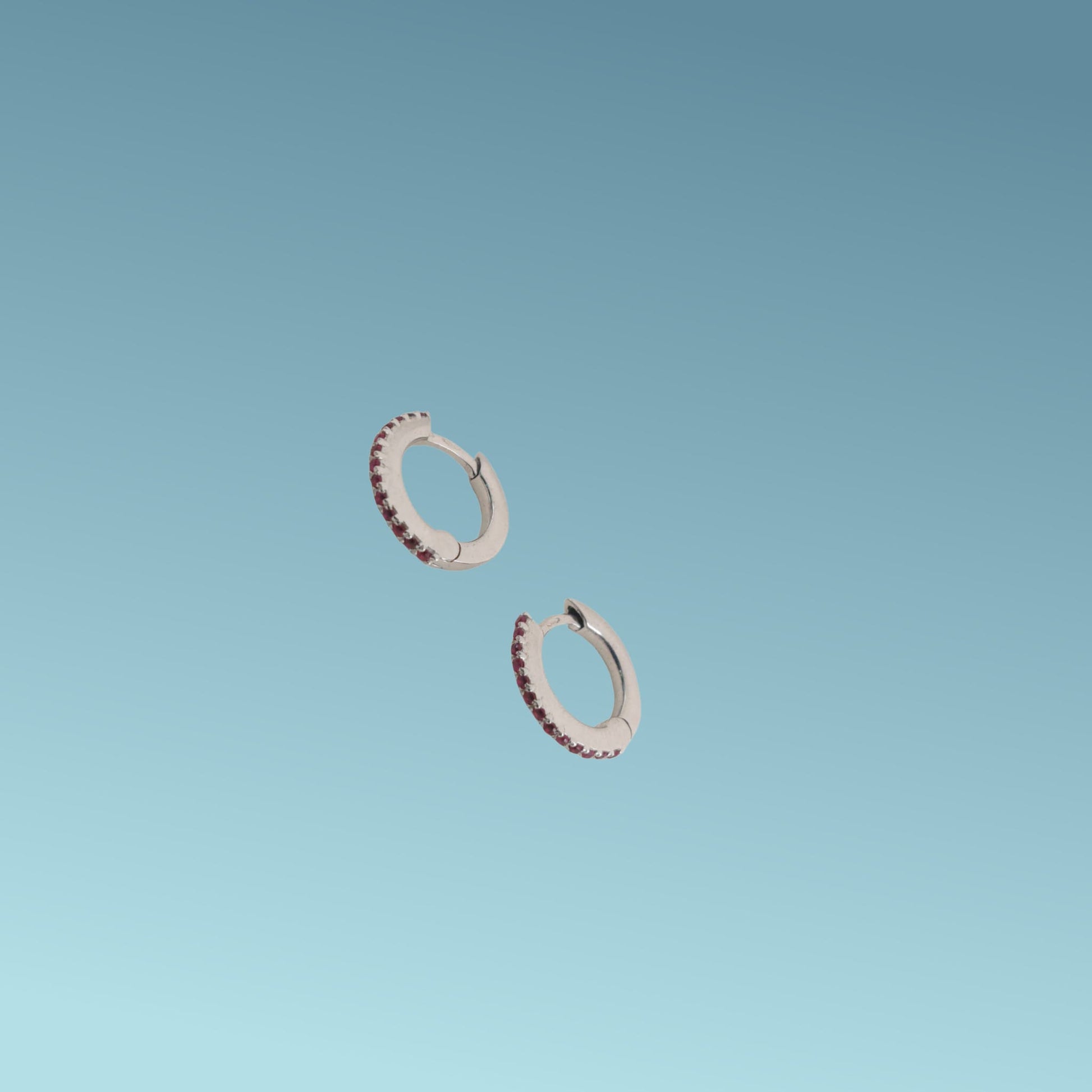 Orecchini in oro bianco 18kt di Meteore Gioielli a forma di cerchio diametro 11mm con una fila di rubini naturali taglio brillante per un totale di 0.16 ct