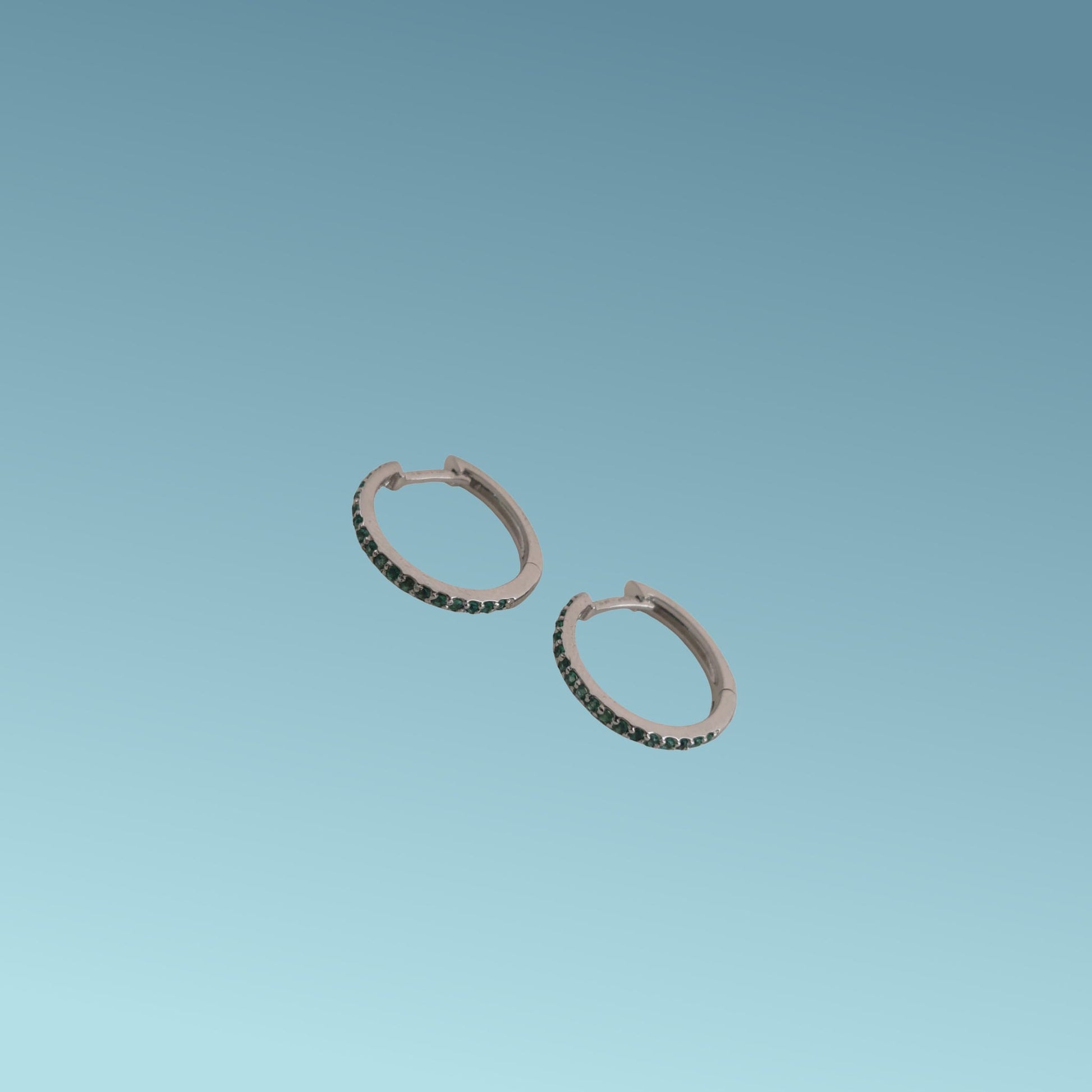 Orecchini in oro bianco 18kt di Meteore Gioielli a forma di cerchio diametro 16mm con una fila di smeraldi naturali taglio brillante incassati a griffes di 0.21ct