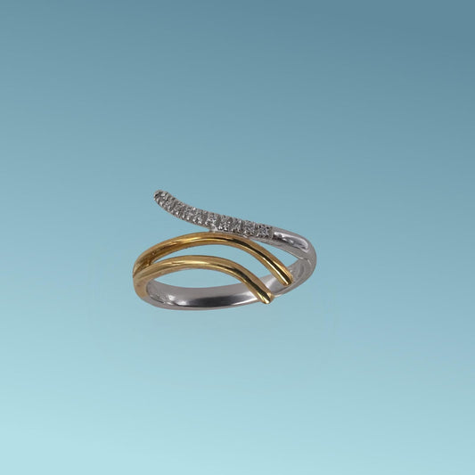 L'anello in oro bianco e giallo 18kt di Meteore Gioielli presenta tre linee ondulate che si incontrano al centro con diamanti naturali taglio brillante ct 0.05