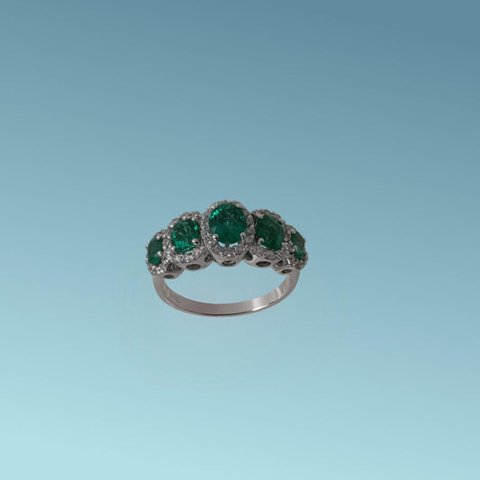 L'anello con smeraldi in oro bianco 18kt di Meteore Gioielli presenta 5 smeraldi ovali con dimensioni a scalare circondati da  diamanti naturali  di 0.43 ct 