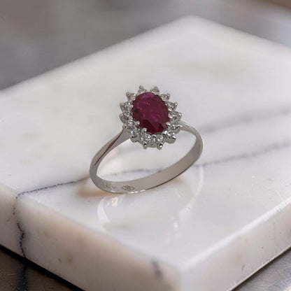 Primo piano, Anello in oro 18 kt con rubino ovale 0,65 ct e contorno di diamanti 0,23 ct. Scopri l'eleganza Meteore Gioielli: qualità artigianale