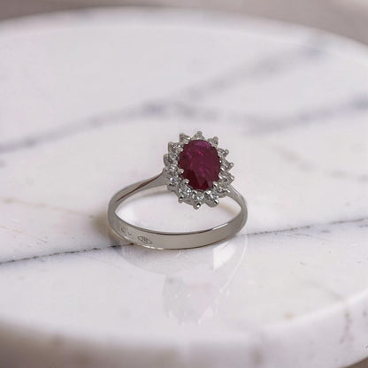 Anello in oro 18 kt con rubino ovale 0,65 ct e contorno di diamanti 0,23 ct.