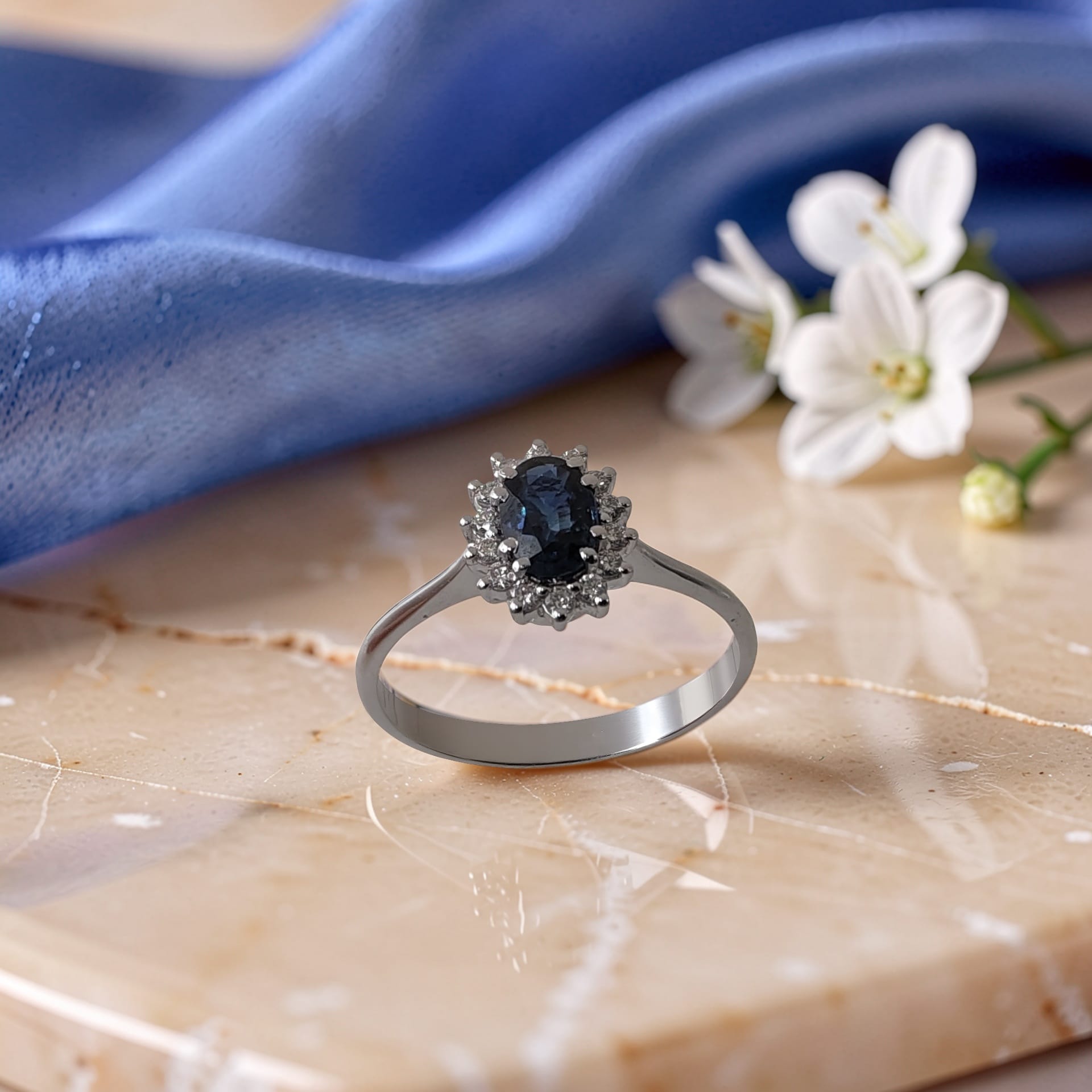 Anello in oro 18 kt con zaffiro naturale ovale da 0,58 carati e contorno di diamanti taglio brillante da 0,12 carati totali.