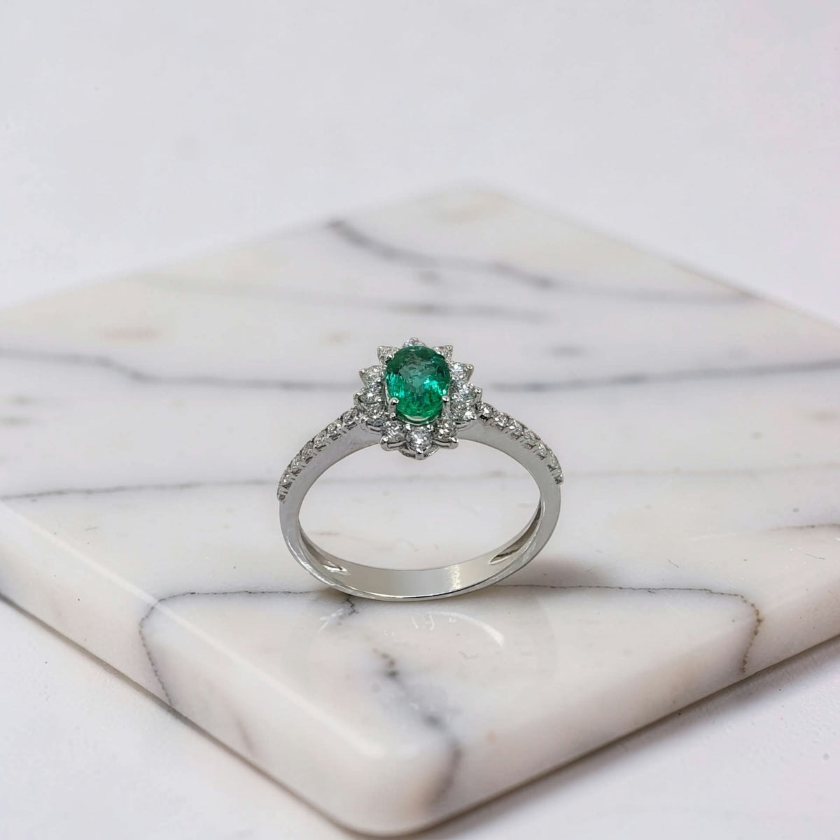 anello oro bianco 18kt con smeraldo naturale ovale 0,45 ct e halo di diamanti e diamanti sul gambo