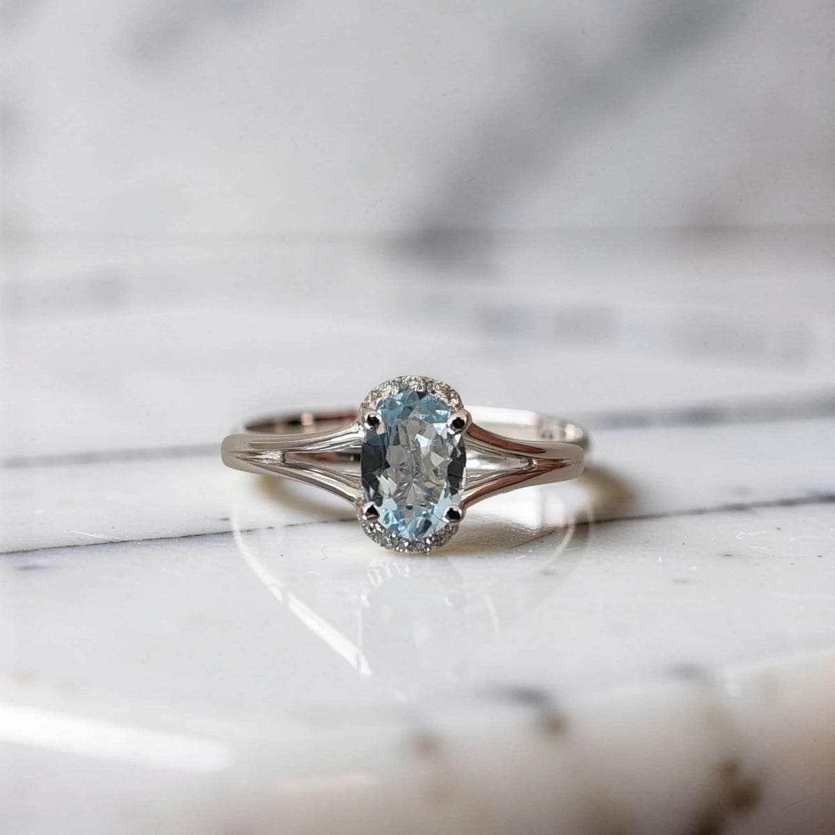vista frontale anello in oro bianco 18 kt con acquamarina ovale 0.69 ct e 8 punti di diamanti sui lati corti. design meteore gioielli.
