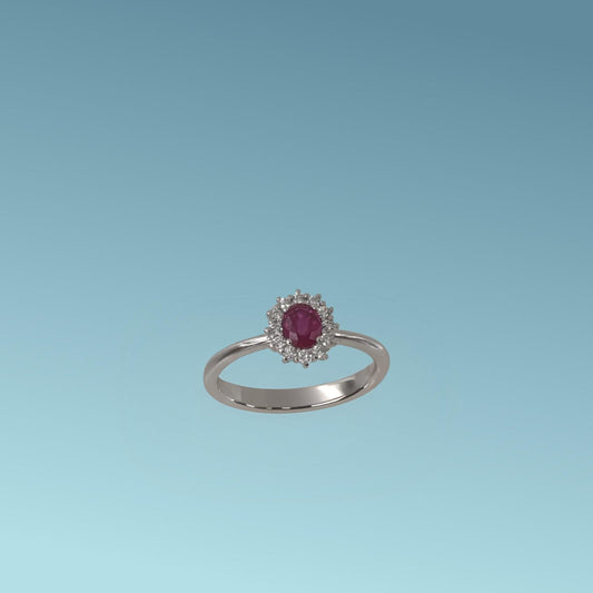 Anello con Rubino di Meteore gioielli Realizzato in Oro Bianco 18k,  presenta al centro un rubino naturale da 0.19 carati taglio ovale, incorniciato da una fila di diamanti naturali taglio brillante ct 0.10 G/VS.