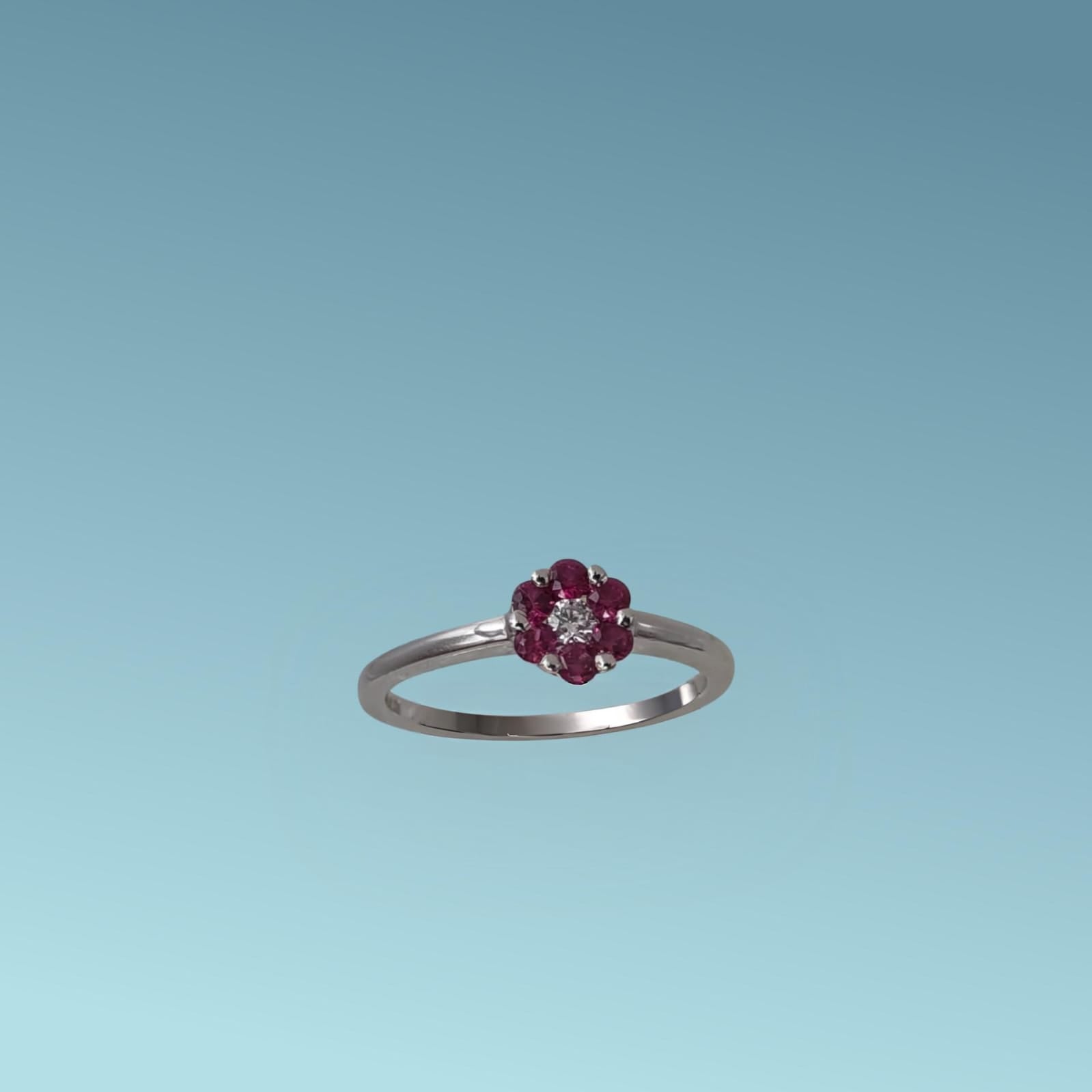 Anello con Rubino di Meteore Gioielli, realizzato in Oro Bianco 18k, presenta al centro un diamante naturale ct 0.05 incorniciato da 6 rubini naturali ct 0.30