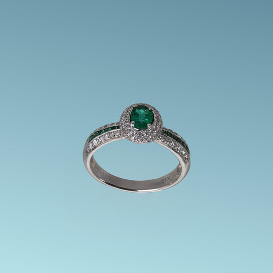 anello di meteore gioielli con smeraldo ovale centrale contornati da diamanti. Sui lati dell'anello ci sono tre binari di diamanti e smeraldi