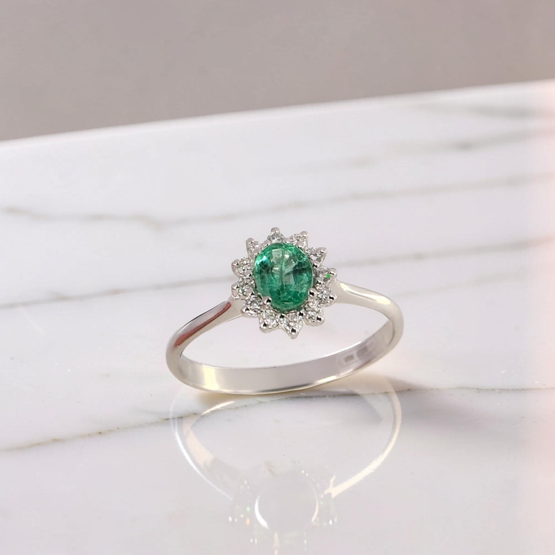 Anello in oro bianco 18kt, smeraldo naturale 0,36 ct, diamanti 0,11 ct G/VS1 a contorno.