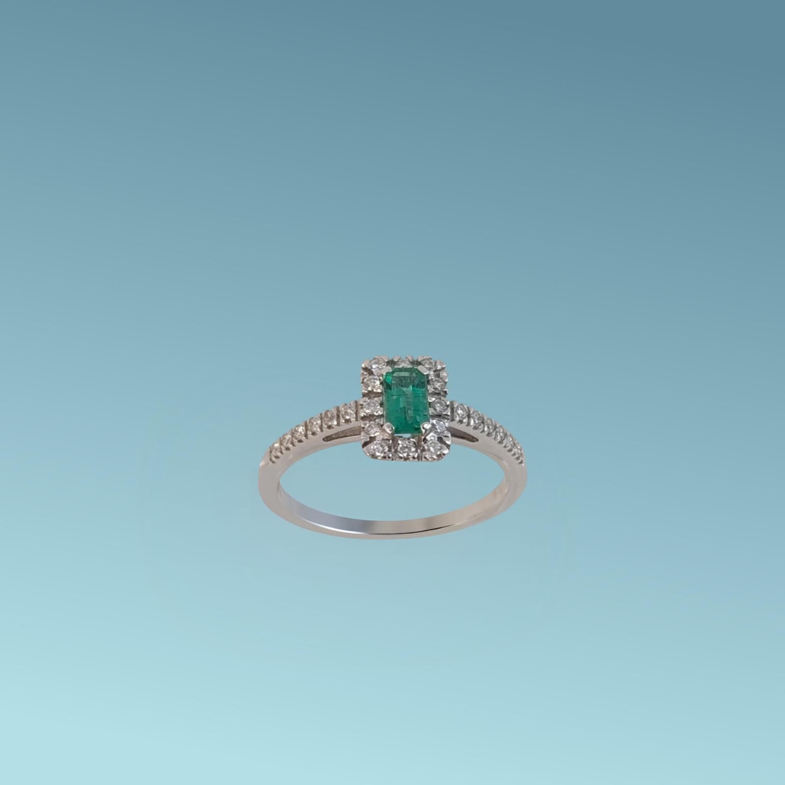 Anello in oro bianco 18kt di Meteore Gioielli presenta uno Smeraldo centrale taglio rettangolare da 0.29 ct e il contorno di diamanti naturali di ct 0.19 G/VS