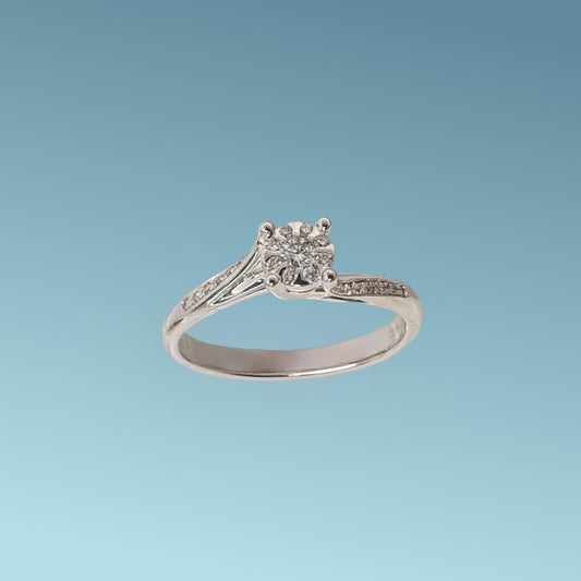 Anello Solitario di Mirco Visconti è  realizzato in oro bianco 18 carati; Il design raffinato presenta una montatura con due fasce impreziosite da piccoli diamanti che si uniscono per sostenere un diamante centrale ct 0.07 e diamanti intorno ct 0.12 G/VS, su un castone tipo "Magic"