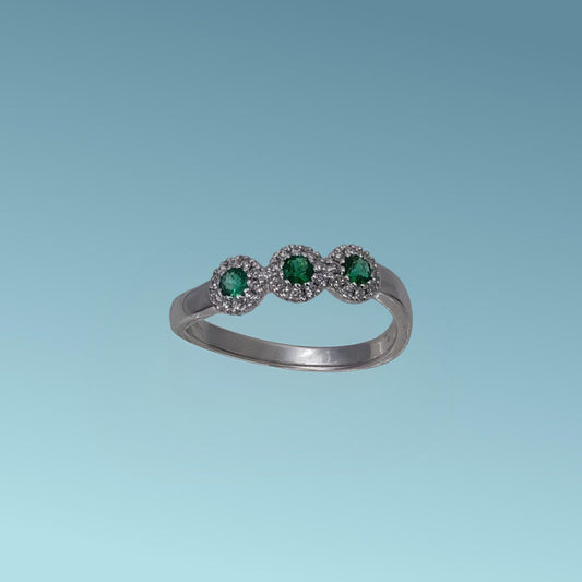 Anello trilogy in oro bianco 18kt di Meteore Gioielli presenta tre  smeraldi per un totale di 0.16 ct, contornato da un pavé di diamanti naturali di 0.10 ct.