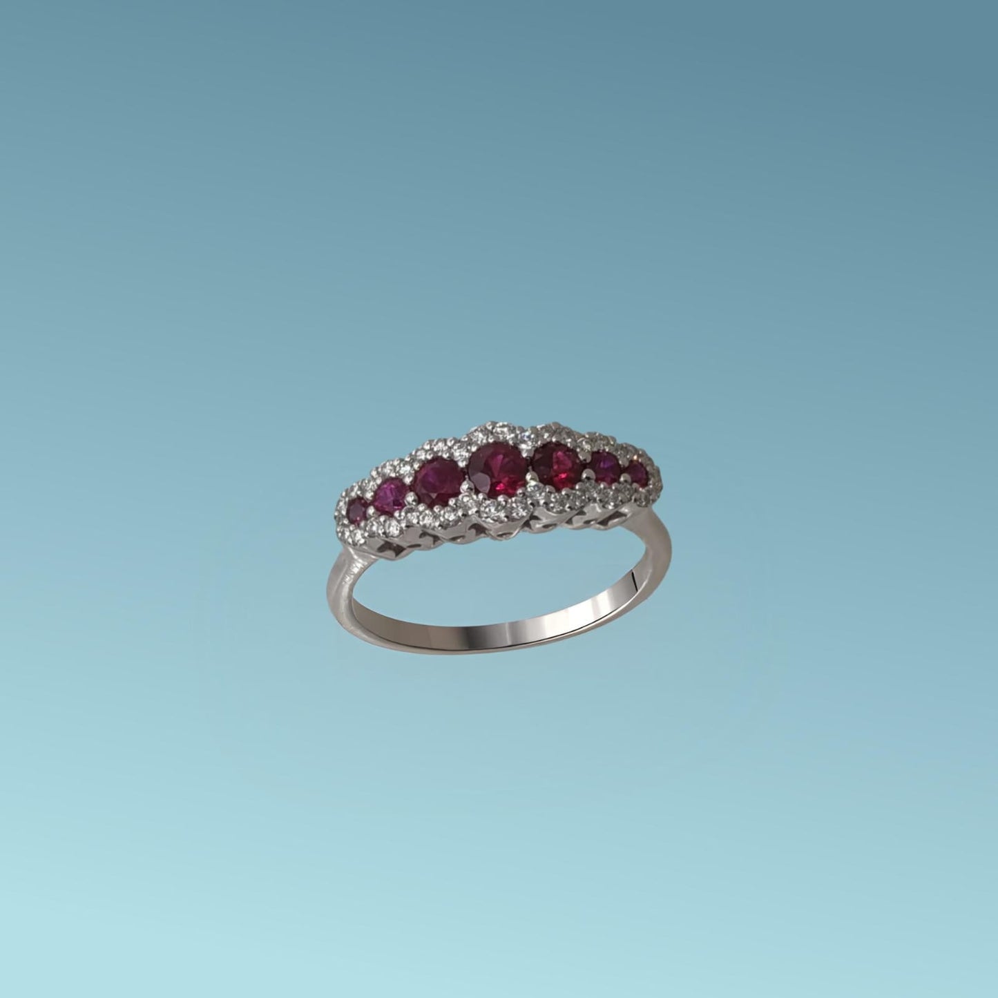 anello con rubini in oro bianco 18kt di mirco visconti presenta una fila di 7 rubini naturali taglio brillante a scalare ai due lati del rubino centrale per un totale di 0.68 ct. intorno ai rubini una coroncina di diamanti naturali taglio brillante per un totale di 0.21 ct,