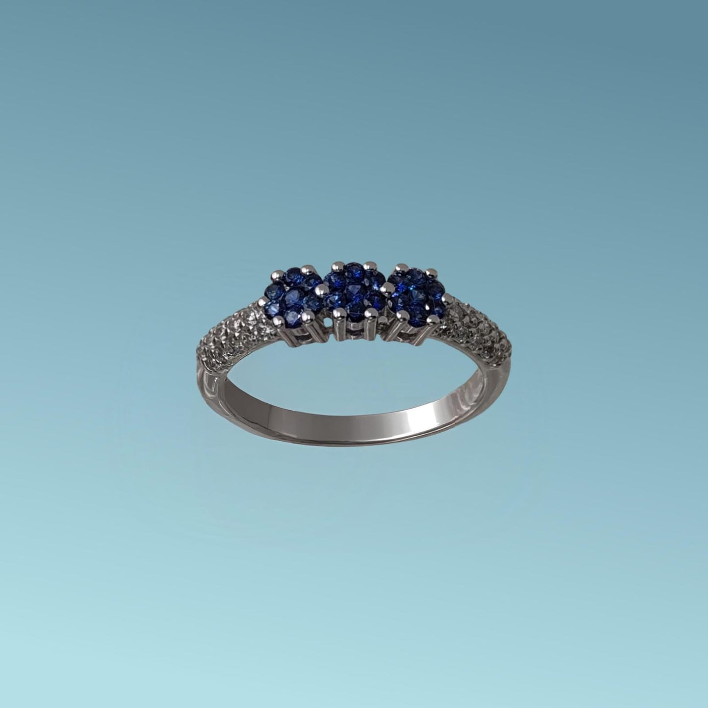 anello trilogy di meteore gioielli con tre rose di zaffiri naturali taglio brillante sapientemente incassati da sembrare tre uniche pietre per un totale di 0.26 ct montate su un gambo in cui è incassato un luminoso pavé di diamanti naturali taglio brillante per un totale do 0.20 ct.