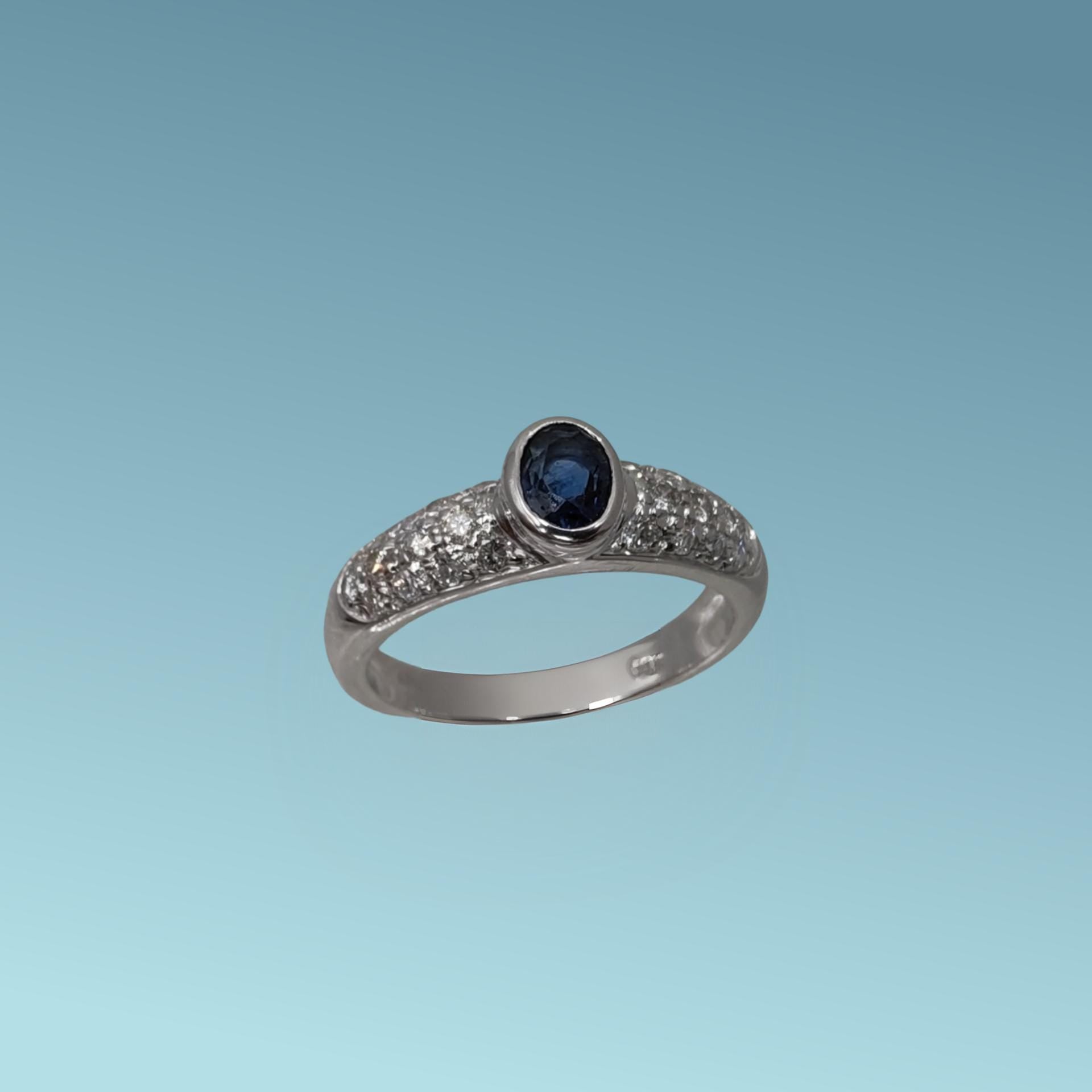 Anello in oro bianco 18kt di Meteore Gioielli con Zaffiro naturale taglio ovale di ct 0.63 incassato su un cestello a bordo battuto con pavè di diamanti ct 0.47