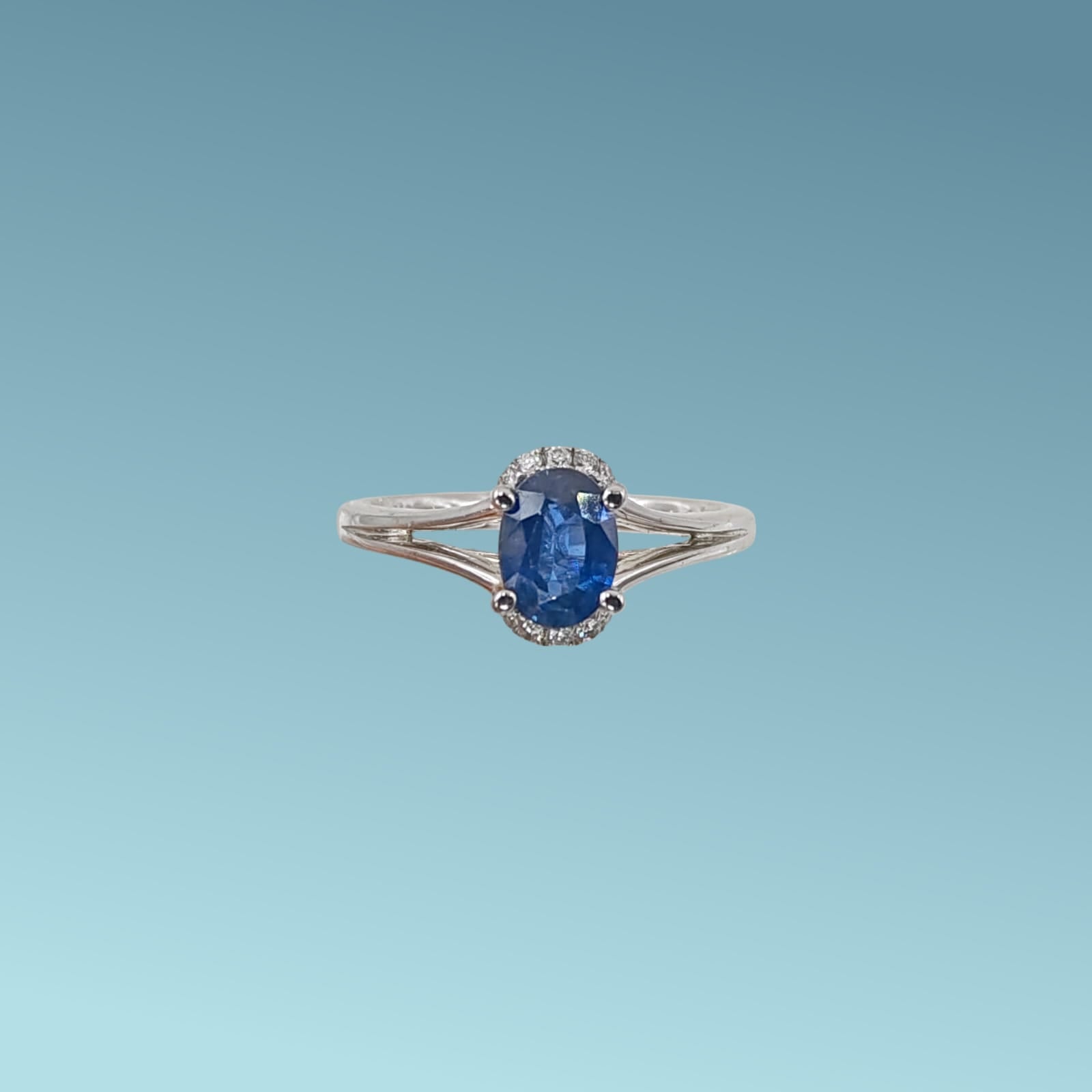 Anello in oro bianco 18kt di Meteore Gioielli con zaffiro naturale taglio ovale ct 1.04 dal blu intenso incassato su un cestello impreziosito da sei piccoli diamanti naturali taglio brillante, per un totale di 0.08 ct, visto da sopra