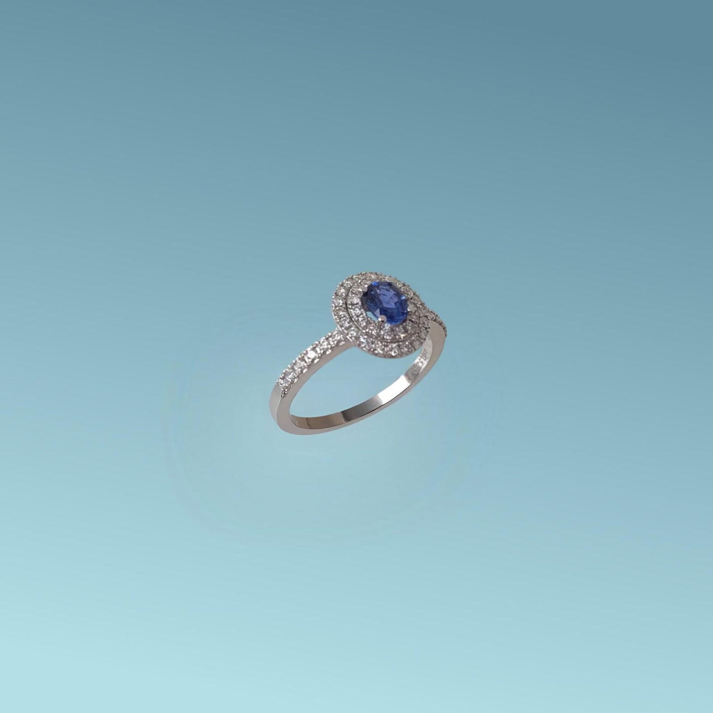 anello in oro bianco 18kt con zaffiro naturale taglio ovale di 0.52 ct e doppio giro di diamanti intorno alla pietra e sul gambo