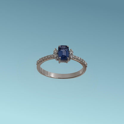 anello con zaffiro blu taglio rettangolare incastonato al centro, abbracciato da quattro diamanti naturali ai lati e   diamanti naturali taglio brillante sul gambo per un totale di 0.19 ct.
