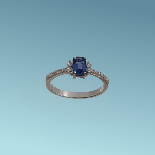 anello con zaffiro blu taglio rettangolare incastonato al centro, abbracciato da quattro diamanti naturali ai lati e   diamanti naturali taglio brillante sul gambo per un totale di 0.19 ct.