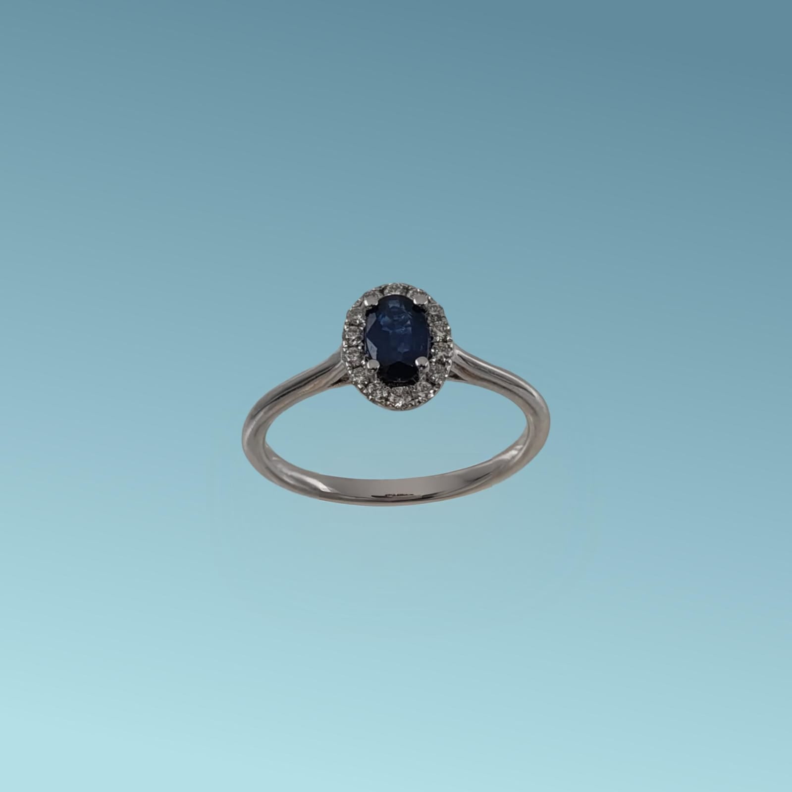 Anello in oro bianco 18kt di Meteore Gioielli con Zaffiro naturale taglio ovale ct 0.46 contornato da un giro di diamanti naturali taglio brillante ct 0.13 G/V