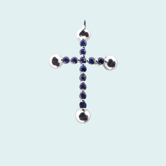 Croce in oro bianco 18 carati con zaffiri blu. Alle 4 estremità della croce ci sono 4 sfere che conferiscono al gioiello più luce e preziosità.