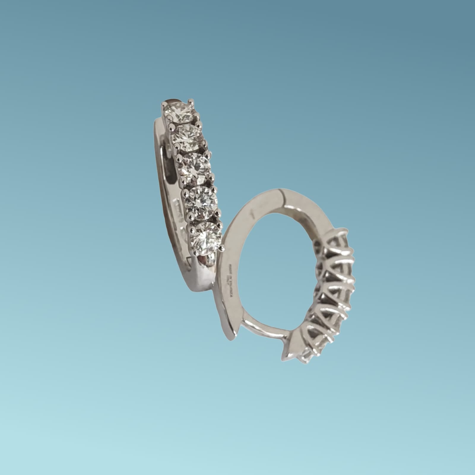 Orecchini a cerchio ovale in oro bianco 18kt di Mirco Visconti presentano una fila di 5 diamanti naturali taglio brillante per un totale di 0.88 ct incassati su castoni a filo su base tond