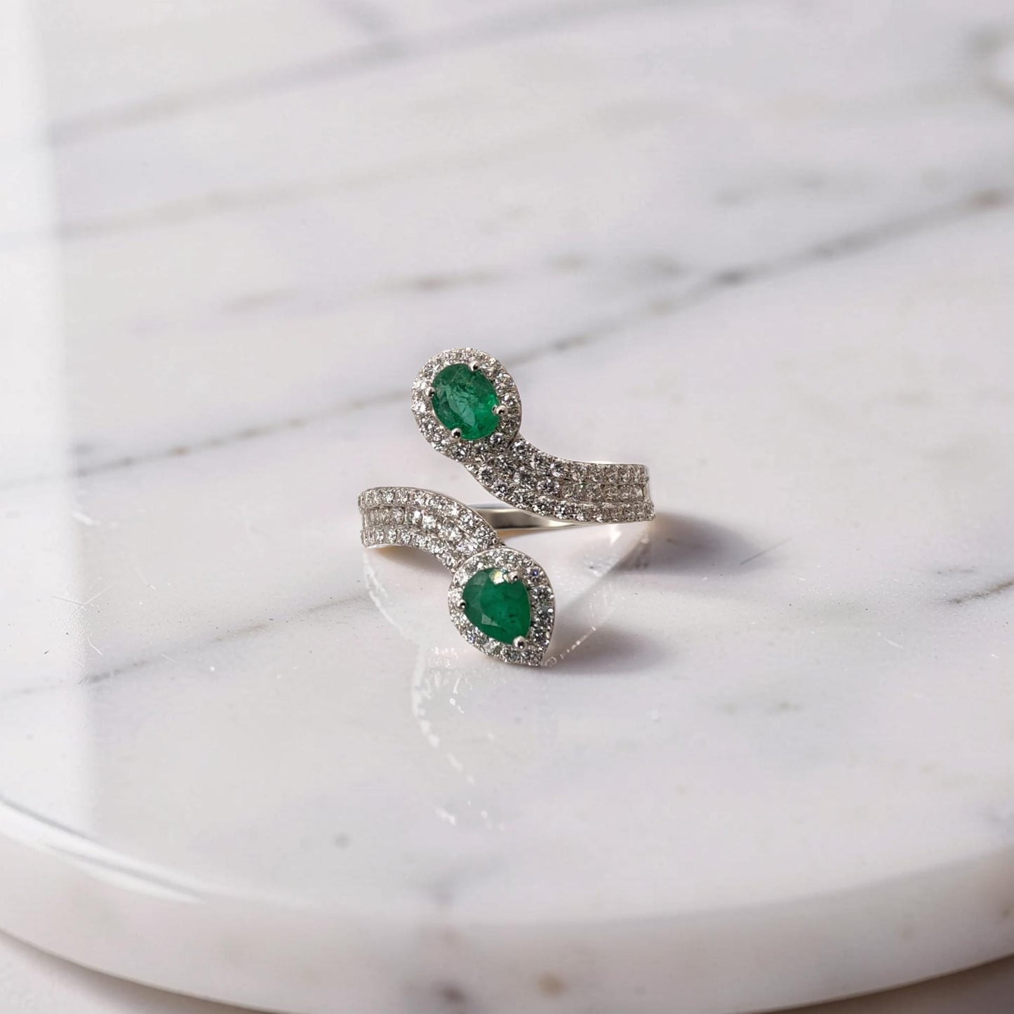 anello contrarié in oro bianco 18 kt con smeraldi naturali da 0,70 ct e pavé di diamanti da 0,58 ct.